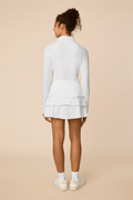 White | Woman wearing a white colored outfit with a Lexi polo shirt and Tulip skort on a beige background