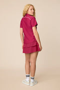 Aurora | Woman wearing the Aurora colored Lexi Polo and tulip skort on a beige background