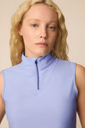 Woman wearing a Stardust colored sleeveless top with a zipper on a beige background
