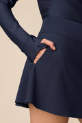 Midnight | Woman wearing a Midnight Taylor Long-Sleeve Half-Zip and skort on a beige background