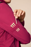 Aurora | Detail of a model wearing a hooded Aurora colored Gabrielle windbreaker with integrated golf tee holders.