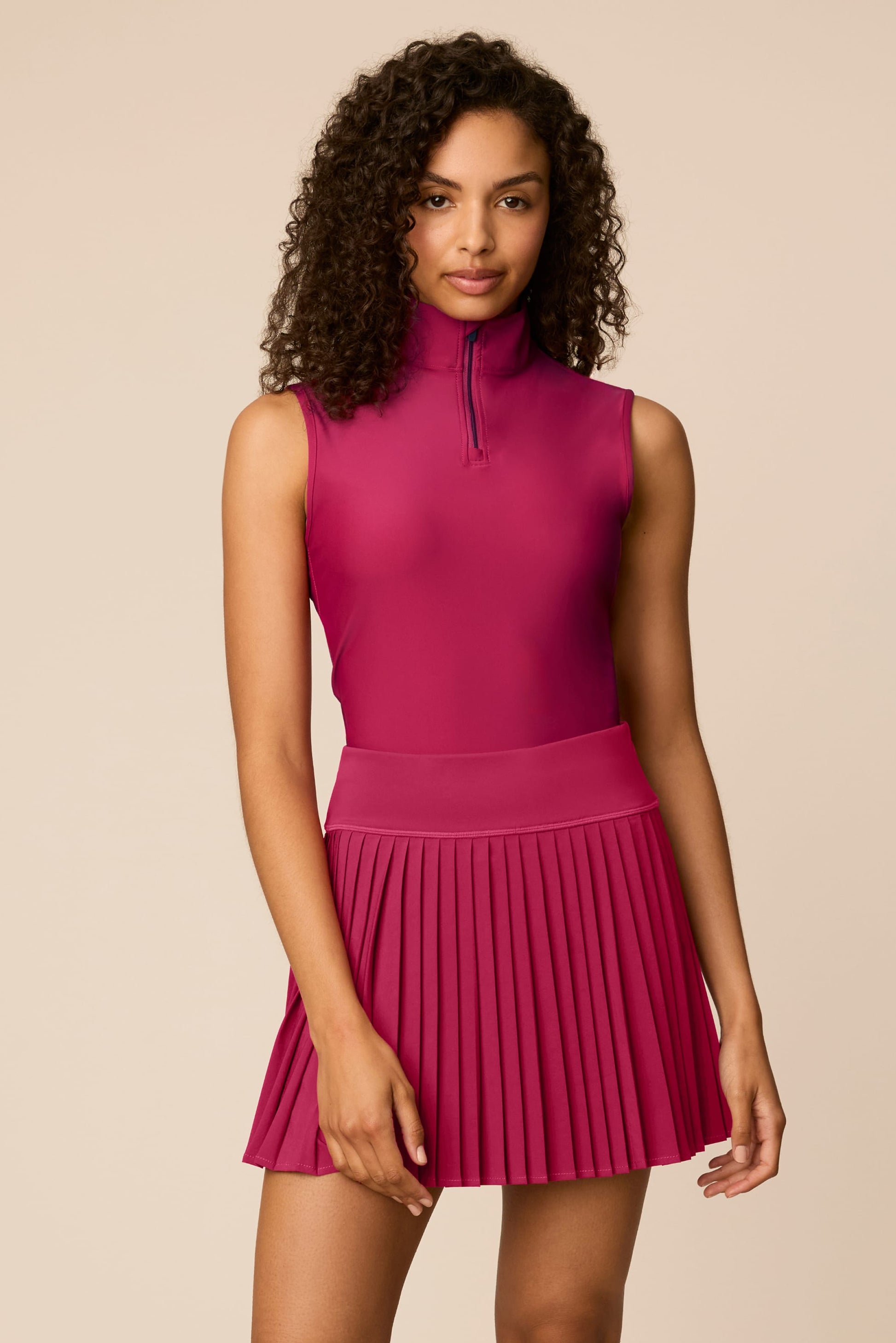 Aurora | Woman wearing The Michelle Pleated Skort 15" pleated skirt on a beige background