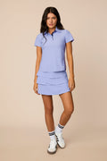 Stardust | Woman wearing a Stardust colored outfit with a Lexi polo shirt and Tulip skort on a beige background