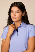 Woman wearing a Stardust colored polo shirt against a beige background