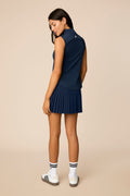 Midnight | Woman wearing a midnight sleeveless top and pleated skort on a beige background