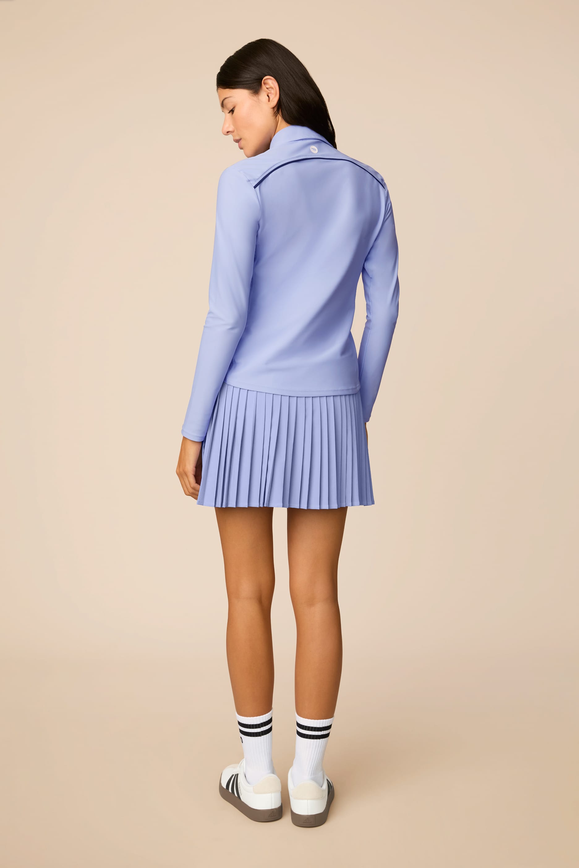Stardust | Woman wearing The Michelle Pleated Skort 15" pleated skirt on a beige background