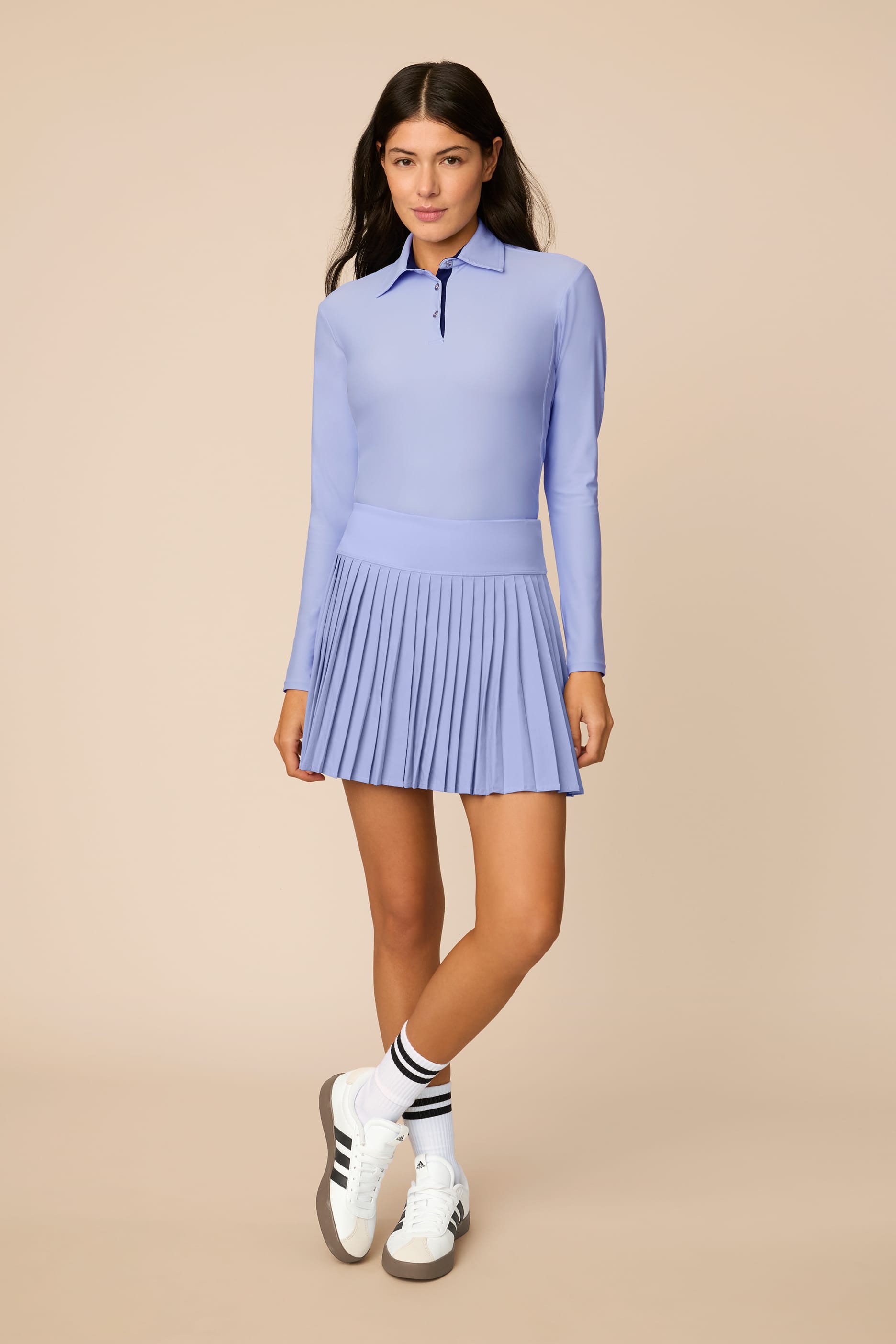 Stardust | Woman wearing a Stardust colored pleated skirt on a beige background
