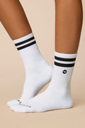 White socks with black stripes worn by a person on a beige background