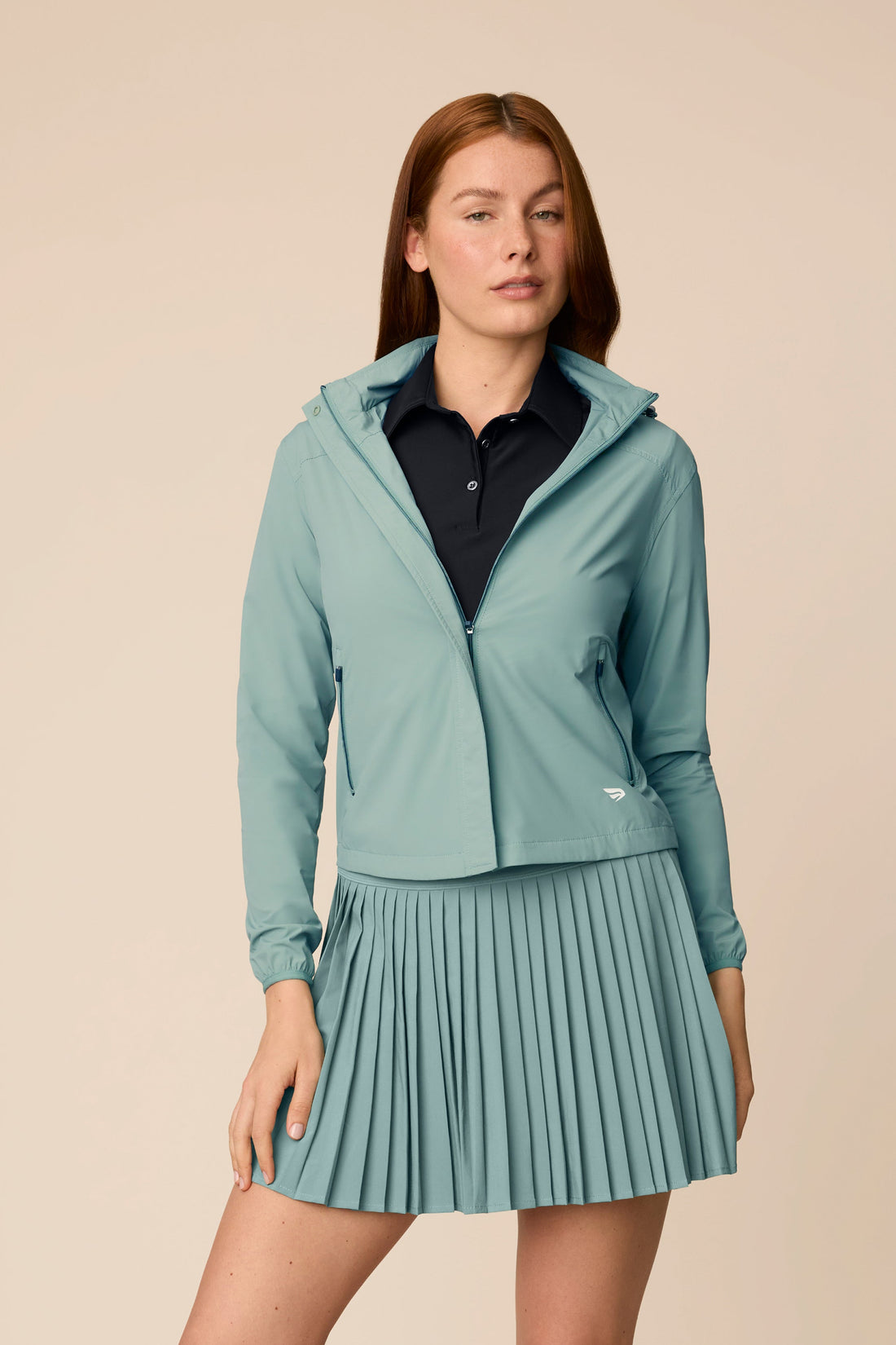 Meadow Haze | Model wearing a hooded Meadow Haze Gabrielle windbreaker with pleated skort.