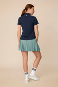 Midnight | Woman wearing the Midnight colored Lexi Polo and skort on a beige background
