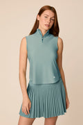 Meadow Haze | Woman wearing a Meadow Haze colored sleeveless top with a zipper on a beige background