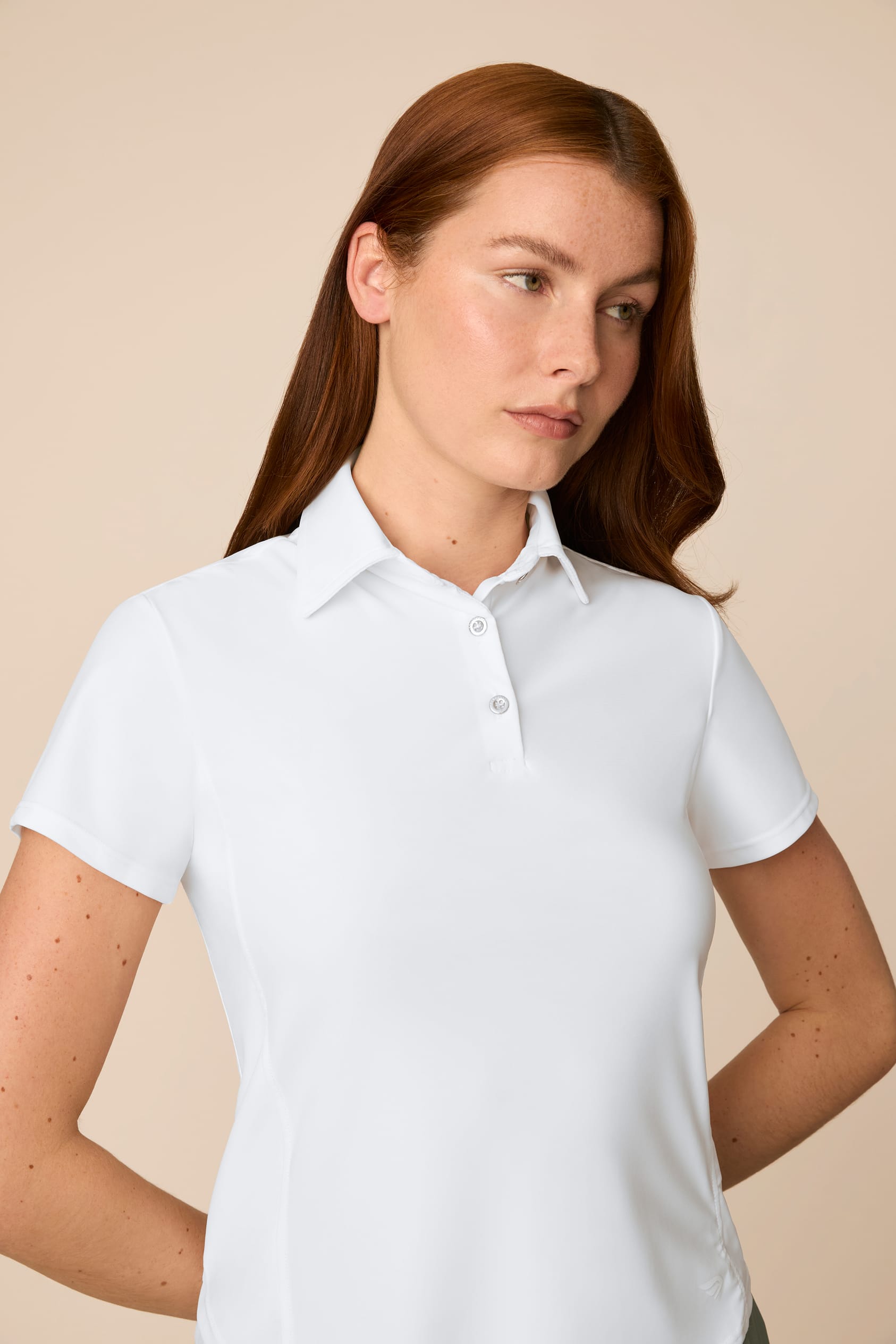 White | Woman wearing the white colored Lexi Polo and skort on a beige background