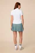 White | Woman wearing the white colored Lexi Polo and skort on a beige background