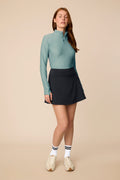 Meadow Haze | Woman wearing a Meadow Haze Taylor Long-Sleeve Half-Zip and skort on a beige background