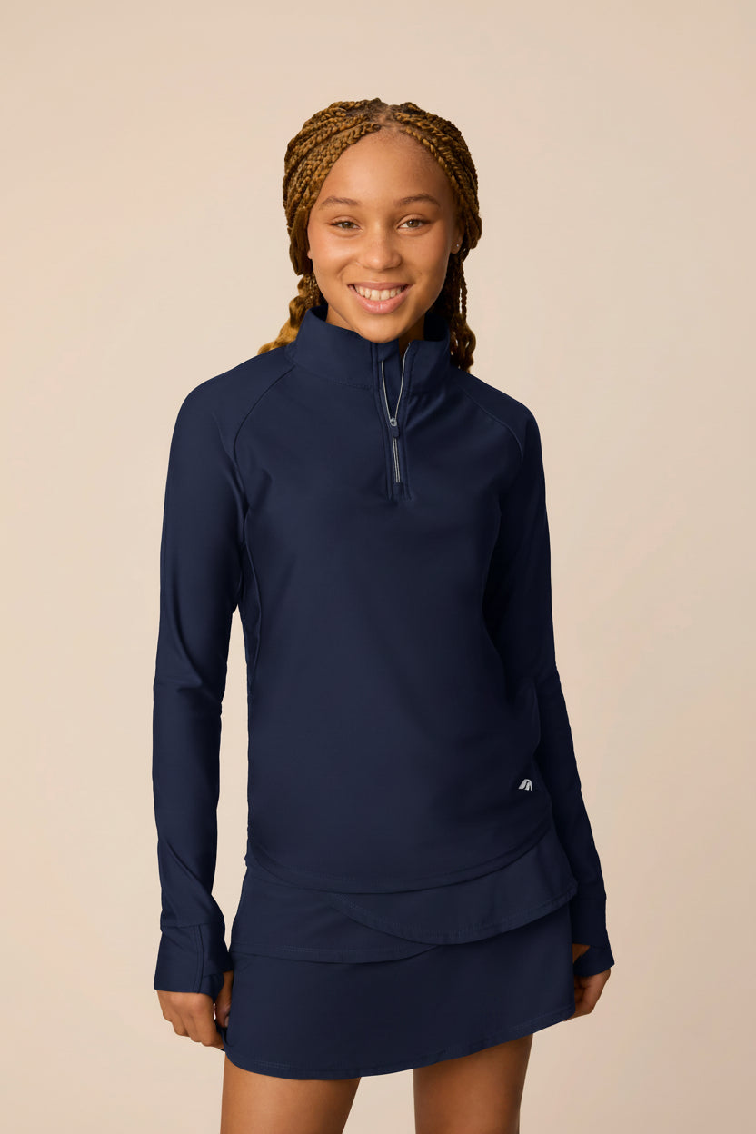 Midnight | Junior golfer in a Midnight color quarter-zip long sleeve shirt on a beige background