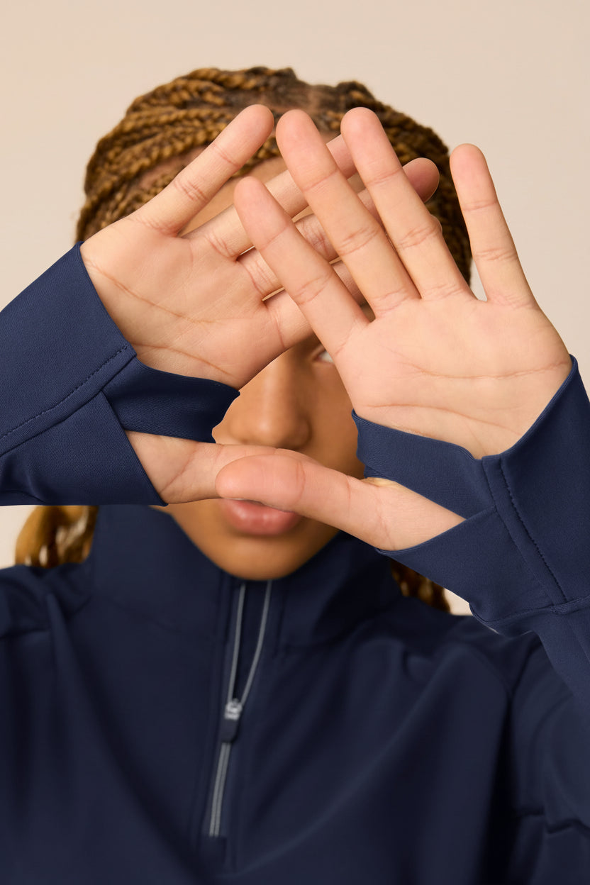 Midnight | Junior golfer in a Midnight color quarter-zip long sleeve shirt on a beige background