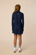Midnight | Junior golfer in a Midnight color quarter-zip long sleeve shirt on a beige background