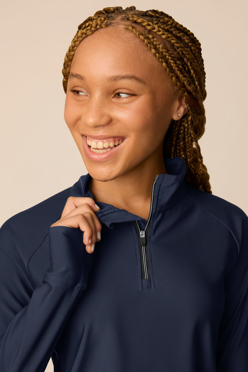 Midnight | Junior golfer in a Midnight color quarter-zip long sleeve shirt on a beige background