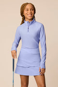 Junior golfer in a Stardust color quarter-zip long sleeve shirt on a beige background