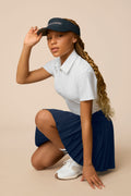 Midnight | Junior golfer wearing a Midnight color pleated skort on a beige background