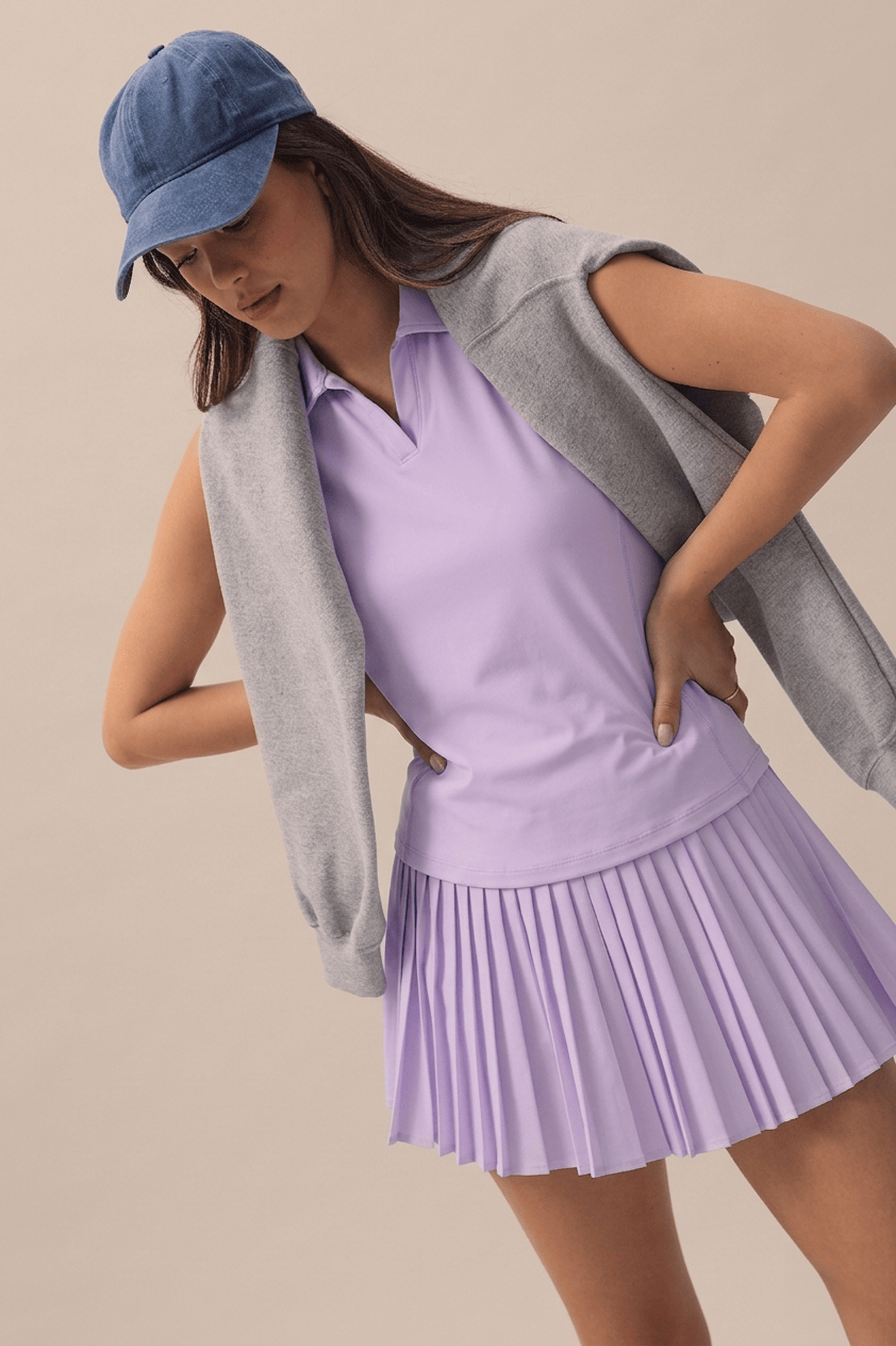 Lilac | Model wearing a denim cap, lilac skort and lilac top.