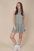 Meadow Haze | Woman wearing a Meadow Haze colored sleeveless top with a zipper on a beige background
