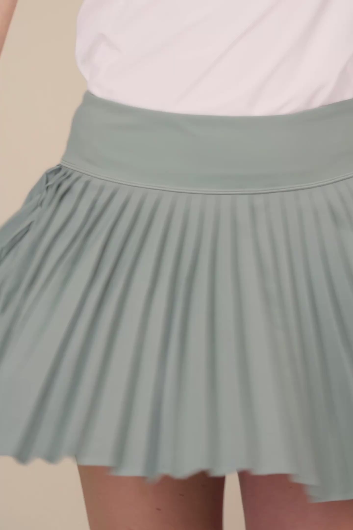 Meadow Haze | Woman wearing a Meadow Haze colored Michelle pleated skort on a beige background