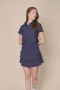 Midnight | Woman wearing the Midnight colored Lexi Polo and tulip skort on a beige background