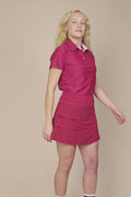 Aurora | Woman wearing the Aurora colored Lexi Polo and tulip skort on a beige background