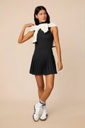 Black | Woman wearing a black colored pleated skirt on a beige background